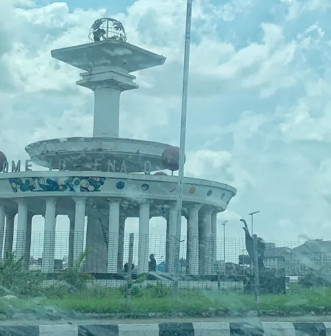 A white circular monument with a column-ringed base and a tower on top, photographed through a windscreen