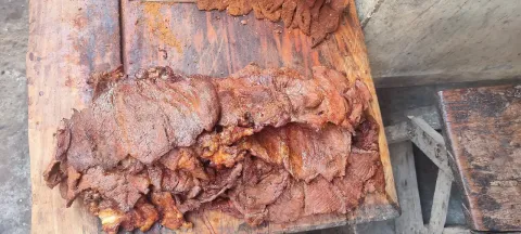Sliced, spice-crusted grilled suya meat piled on a wooden board