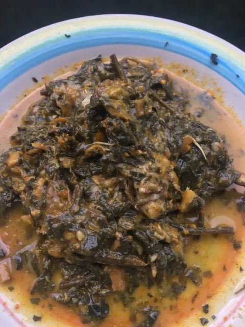 A round bowl of dark, leafy bitterleaf soup in a broth